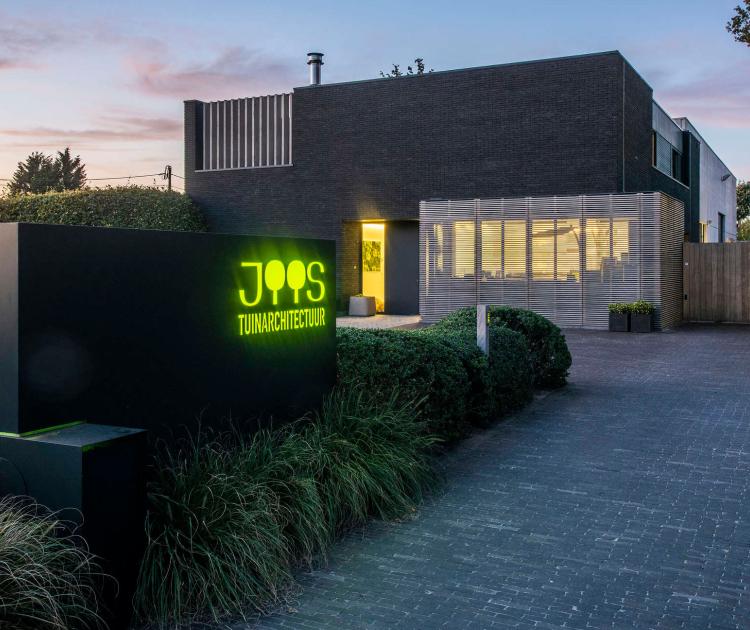 Huis met logo van Tuinen Joos in de voortuin