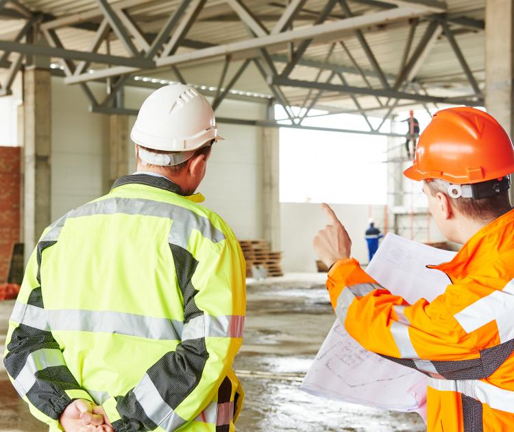 2 werkmensen met helm en veiligheidsjas in magazijn